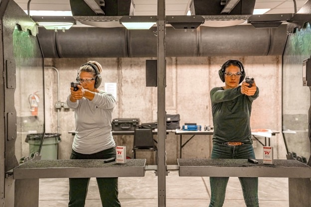 Two women at a shooting range aiming downrange.
