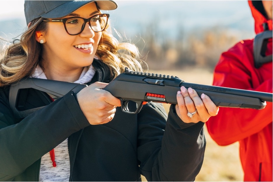 Smiling woman aiming a Winchester Firearms Wildcat .22 LR rifle